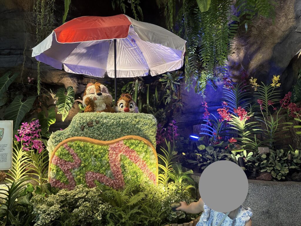お花で作られたチップとデールの展示を見る子ども