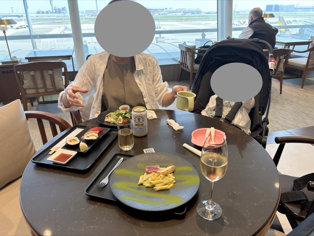 ラウンジのテーブルに並んだ食事と、隣のベビーカーに座る娘