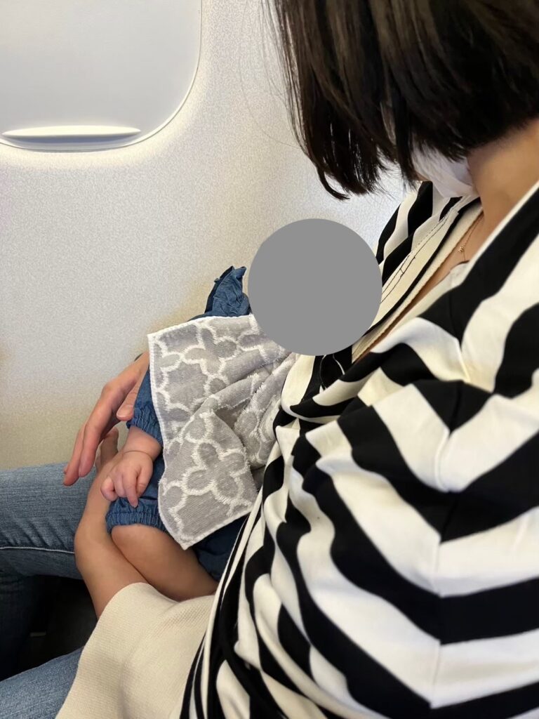 飛行機の中で抱っこされる生後2ヶ月の娘