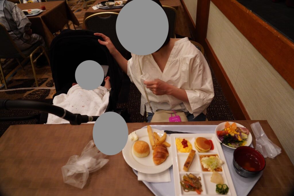 朝食ビュッフェのテーブルとベビーカーの娘