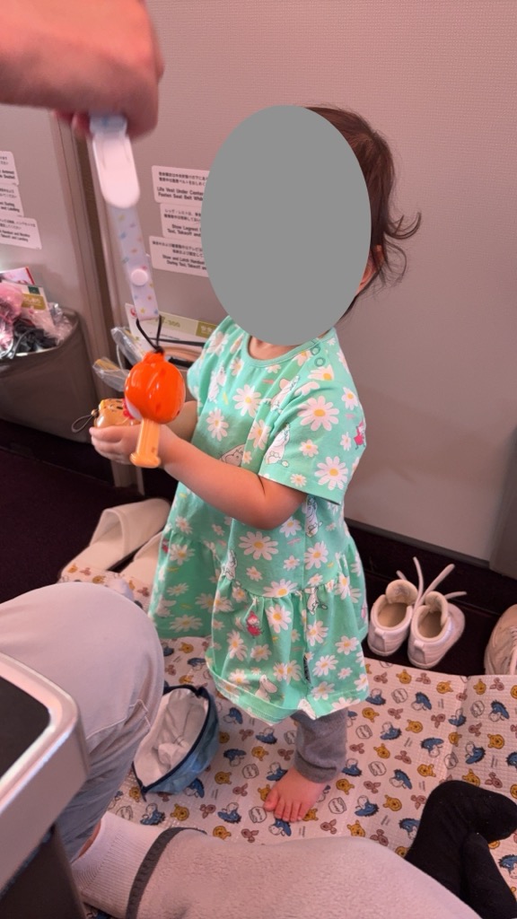 機内のいちばん前の席の足元で立つ1歳半の娘